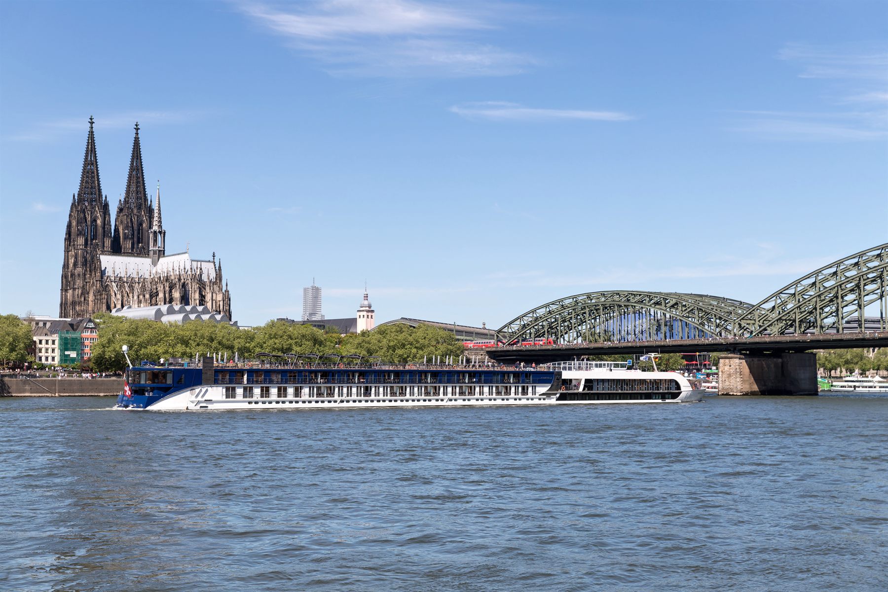 River cruise ship on the Rhine below Cologne Cathedral and the Hohenzollern Bridge