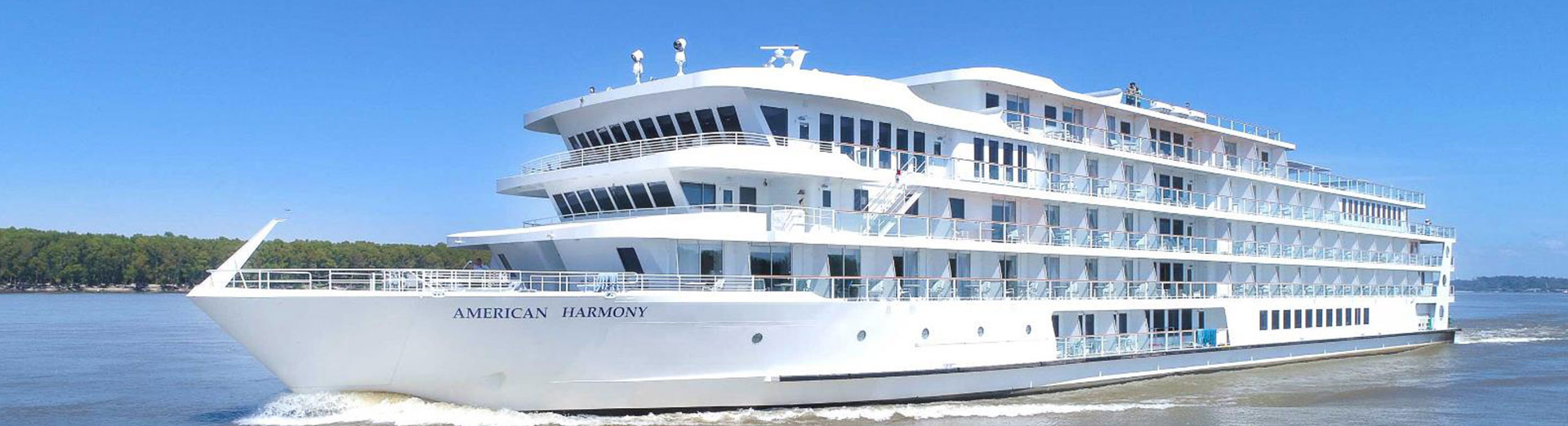 The riverboat American Harmony cruising a calm, tree-lined river